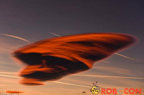 Đám mây hình thấu kính đỏ rực giữa những vệt trắng do máy bay tạo ra trên bầu trời thị trấn Gevgelija ở Macedonia. Hiện tượng này xảy ra khi luồng không khí ẩm gặp các chướng ngại vật như núi cao hay các tòa nhà.