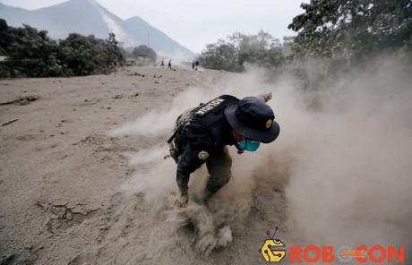 Một cảnh sát loạng choạng khi chạy khỏi nham tầng núi lửa Fuego.