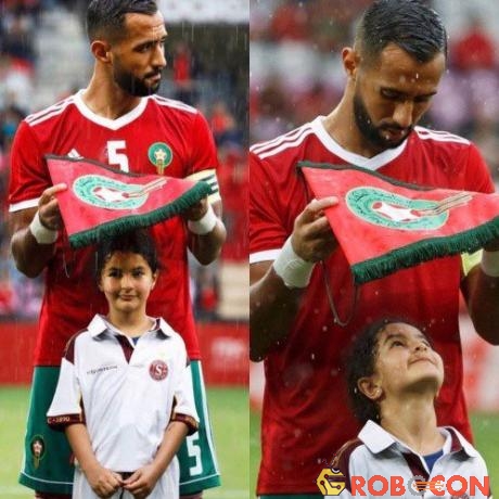 Medhi Benatia - đội trưởng đội tuyển Ma Rốc lấy lá cờ hiệu che mưa cho bé gái đại diện cho anh.