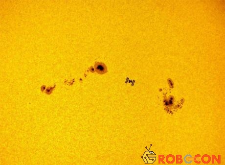 Trạm vũ trụ quốc tế (ISS) với background là mặt trời với những điểm đen lớn trên bề mặt