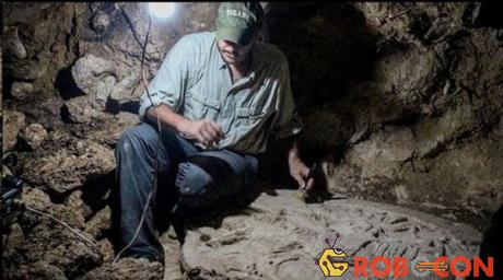 Nhà khảo cổ học Tulane, Marcello A. Canuto, ngồi bên cạnh bàn thờ mà nhóm của ông đã khám phá trong khu rừng nhiệt đới miền bắc Guatemala