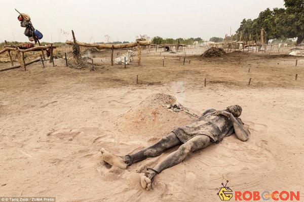 Người đàn ông này thư giãn trên lớp tro mềm mịn cạnh đống lửa phân bò đã gần tàn. Loại tro này mịn như bột talcum, bảo vệ cả người và bò khỏi cái nóng như thiêu như đốt của Sudan.